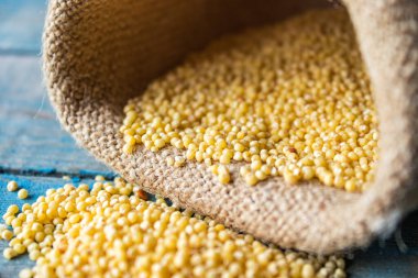 Çiğ sarı darı torbanın yanındaki mavi tahtalara saçılmış..