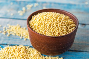 Eski mavi tahtaların arka planında bir kasede kurumuş sarı darı.