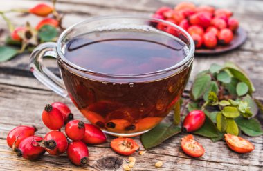Kırmızı böğürtlenlerin yanında ahşap bir masada bir fincan gül çayı..