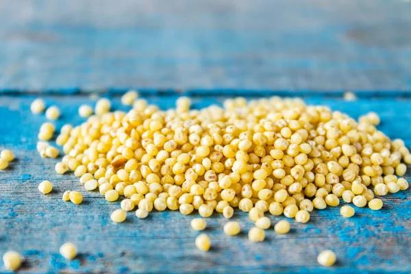 Eski mavi tahtalarda bir yığın kuru sarı darı yatıyor..