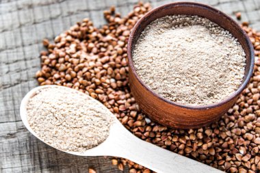 Karabuğday unu karabuğday tanesinin yanında bir kasede ve unlu bir kaşık. Bir yığın karabuğday unu..