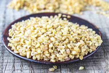 Bir kasede kuru bulguru taneleri. Bir yığın çiğ Bulgur lapası. Sağlıklı, besleyici, vegan, glütensiz ürün. Sağlıklı beslenme konsepti. Buğday tanelerinden yapılan organik ürün.