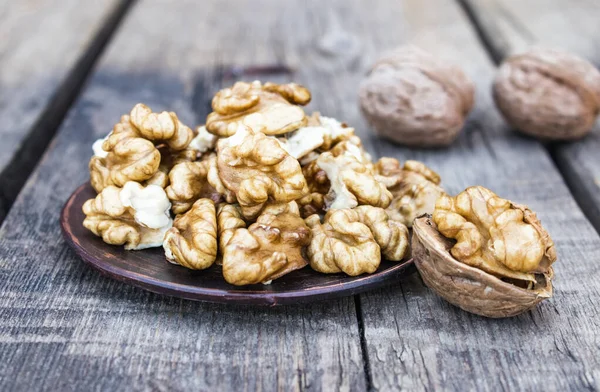 Les noyaux de noix se trouvent dans un bol sur une vieille table en bois rustique. Noix fraîches . — Photo