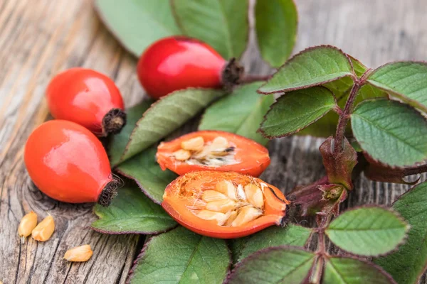 Kırmızı gül kalçalar ve olgunlaşmış böğürtlenler eski ahşap tahtalarda tohumlarla.