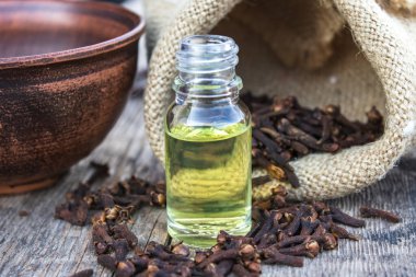 Baharat karanfili, cam bir şişede, eski ahşap tahtaların üzerinde, kuru karanfil baharatlarının yanında..