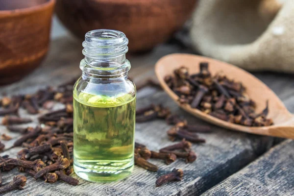 Baharat karanfili, cam bir şişede, eski ahşap tahtaların üzerinde, kuru karanfil baharatlarının yanında..