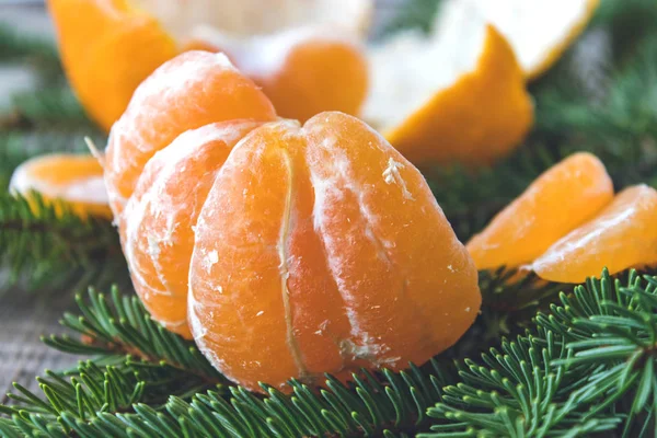 Le fette sbucciate mature di mandarino senza buccia si trovano sui rami verdi di un albero di Natale. . — Foto Stock