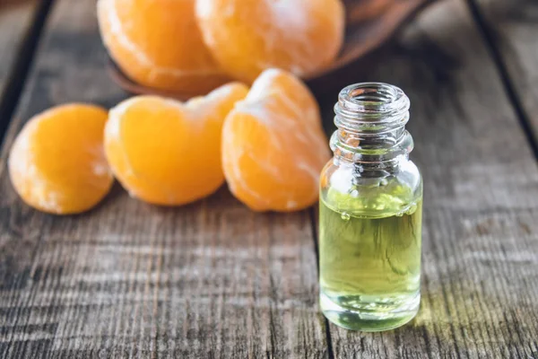 Huile essentielle de mandarine et tranches de mandarine jaune mûre posées sur une table en bois . — Photo