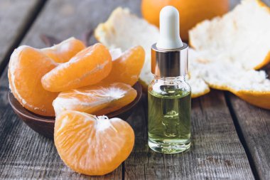 Kabuksuz olgun mandalina dilimleri ve masada mandalinalı bir şişe gerekli yağ..