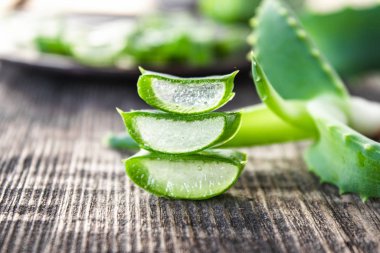 Taze aloe vera yaprakları ve ahşap bir arka planda aloe vera dilimleri..