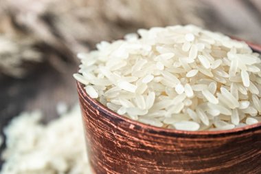 Eski tahtaların arka planında pirinç yığınının yanında bir kase beyaz pirinç. Yasemin pilavı..