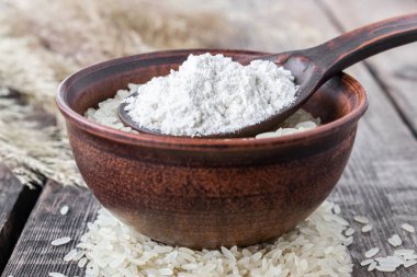 Eski tahtaların arka planında beyaz un olan bir kasede beyaz pirinç. Yasemin pilavı..