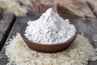 Pirinç unu eski tahtalarda bir yığın beyaz pirinç üzerinde kaşıkta.