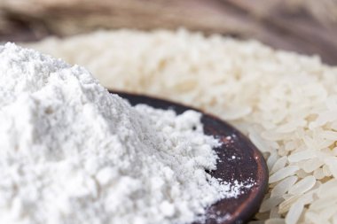 Pirinç unu eski tahtalardaki beyaz pirinç yığınının yanında bir kasede. Yasemin pilavı..