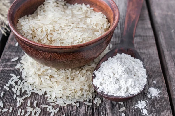 Eski tahtaların arka planında beyaz un olan bir kasede beyaz pirinç. Yasemin pilavı..