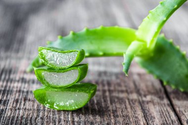 Taze aloe vera yaprakları ve ahşap bir arka planda aloe vera dilimleri..