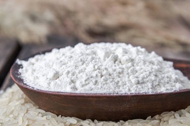 Pirinç unu eski tahtalarda beyaz pirinç yığını üzerinde bir kase içinde.