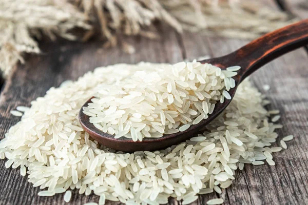 White rice with a wooden spoon on a pile of rice against the background of old boards. Jasmine rice for cooking.