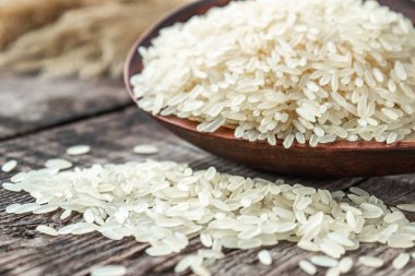 Bir kase beyaz pirinç, eski tahtaların arkasına serpilmiş pirinç serpiştirilmiş. Yasemin pilavı..