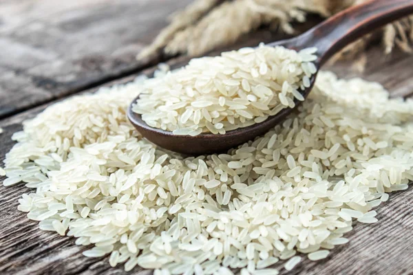 White rice with a wooden spoon on a pile of rice against the background of old boards. Jasmine rice for cooking.