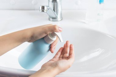 Bir çocuk ellerini beyaz bir lavabonun yanında yıkıyor. El temizliği, dezenfeksiyon, sağlık ve el yıkama kavramı..