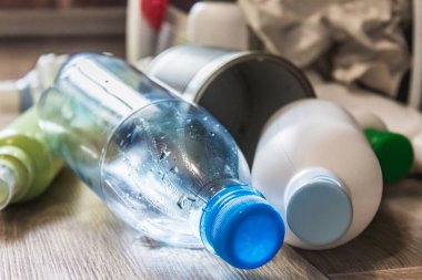 Plastik şişeler, kağıt ve metal kutular mutfak zeminine saçılmış. Çöp atıkları.