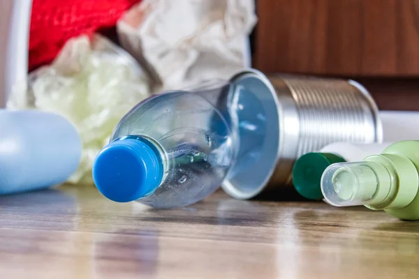 Plastic bottles, paper and metal cans are scattered across the kitchen floor. Garbage waste.