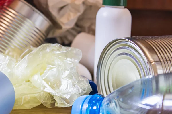 Plastic bottles, paper and metal cans are scattered across the kitchen floor. Garbage waste.