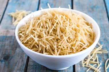 Mavi panoların arka planında bir kasede kuru makarna. Sağlıklı beslenme ya da sağlıklı yaşam tarzı.