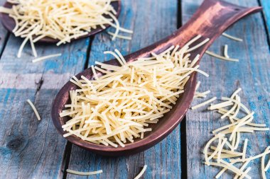 Mavi panoların arka planında büyük bir kaşıkta kuru makarna. Sağlıklı beslenme ya da sağlıklı yaşam tarzı.