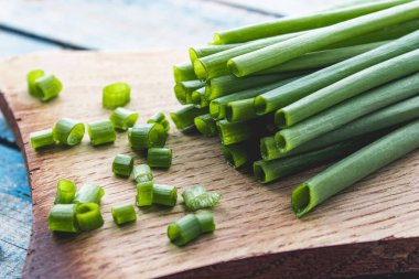 Kesme tahtasındaki dilimlenmiş yeşil soğan halkaları eski mavi tahtaların arka planında. Frenk soğanlarının birçok vitamini ve minerali vardır..