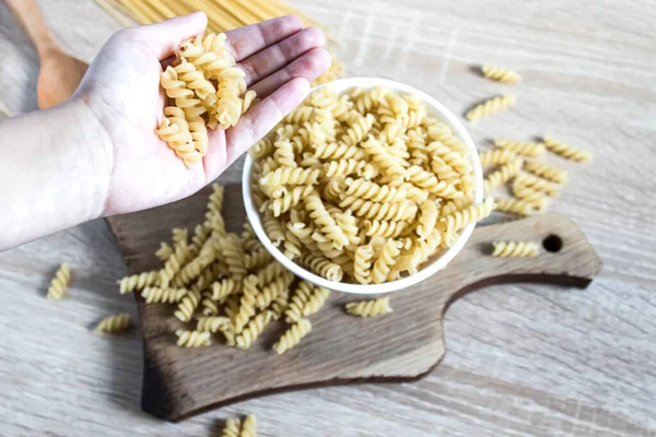 Dry pasta in hands on a background of scattered pasta. Healthy eating or healthy lifestyle.