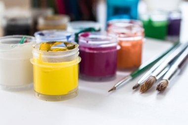 Masanın üzerinde bir kavanozda çok renkli guaj ve boya için fırçalar var. Çizim, yaratıcılık ve hobiler için hazır. Yakın plan..