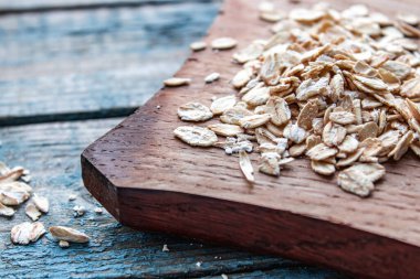 Mavi tahtanın arka planındaki kesme tahtasındaki gri yulaf ezmesi. Sağlıklı beslenme, kahvaltı konsepti.