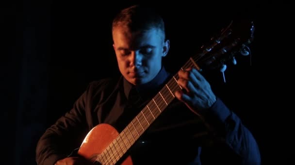 ミュージシャンのヴィルトゥオーゾは黒を背景にクラシック アコースティック ギターを演奏し顔の近くで孤立した — ストック動画