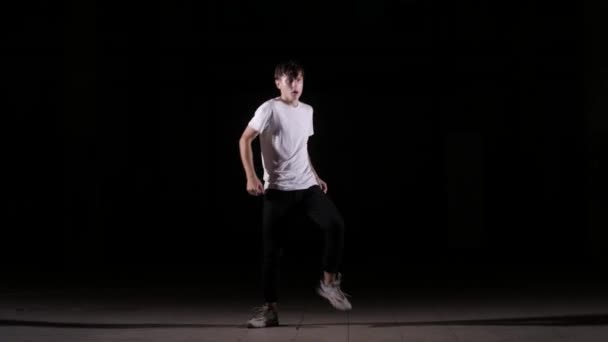 若いダンサーがダンスブレイクダンスヒップホップストリートダンスをスタジオで黒人を背景に孤立させ — ストック動画