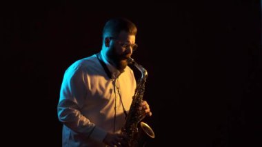 Saksafon çalan yakışıklı adam, siyah arkaplan, soyutlanmış, tek başına.