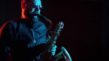 Saksafoncu saksafon çalar, siyah arkaplan, soyutlanmış, tek başına