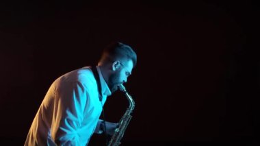 Yakışıklı müzisyen saksafon çalıyor, siyah arkaplan, soyutlanmış, tek başına