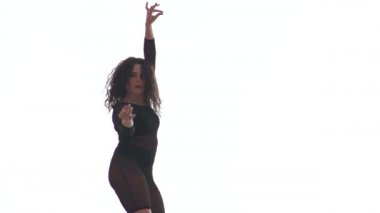 Siyah şeffaf dar takım elbiseli güzel bir kadının uzun pozu enerjik bir şekilde dans salonu, sokak dansı, beyaz arka planda twerk, izole edilmiş.