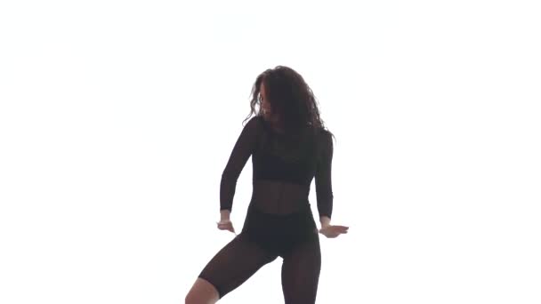 中長いショットの若い美しい女性で黒透明タイトスーツ精力的にダンスホール ストリートダンス 白い背景に対するトーク 隔離されたダンス — ストック動画