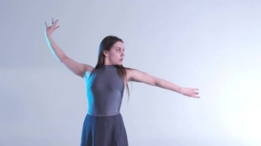 Uzun saçlı, çağdaş dans eden genç ve güzel bir dansçı kız stüdyoda dans ediyor. Renkli arka plan ışığı, yavaş çekim, izole edilmiş, orta boy.
