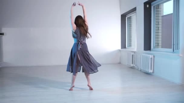 若い美しい女性の長い髪を持つドレス感情的にコンテンポラリーダンス 窓のあるスタジオで現代バレエダンス スローモーション ジンバルショット — ストック動画