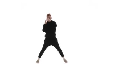 Siyah eşofmanlı genç yakışıklı adam güçlü bir şekilde dans ediyor hip hop, serbest stil, sokak dansı, karmaşık hareketler yapıyor, izole edilmiş.