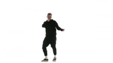 Siyah eşofmanlı genç adam güçlü bir şekilde hip hop, serbest stil, sokak dansı yapıyor. Karmaşık hareketler yapıyor.