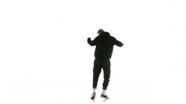 Siyah eşofmanlı genç adam güçlü bir şekilde hip hop, serbest stil, sokak dansı yapıyor. Karmaşık hareketler yapıyor.