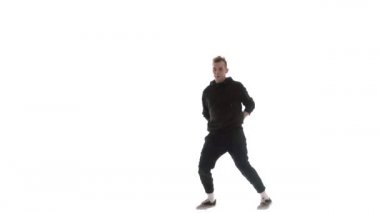 Siyah eşofmanlı genç adam güçlü bir şekilde hip hop, serbest stil, sokak dansı yapıyor. Karmaşık hareketler yapıyor.