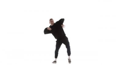 Siyah eşofmanlı genç adam güçlü bir şekilde hip hop, serbest stil, sokak dansı yapıyor. Karmaşık hareketler yapıyor.