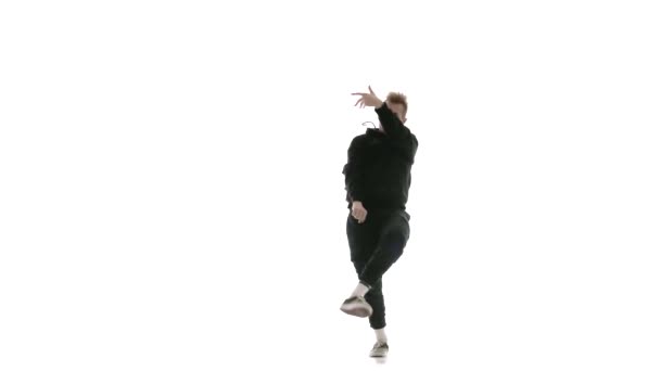 年轻英俊的小伙子身穿黑色运动服 精力充沛地跳嘻哈 自由泳 表演着复杂的动作 孤立无援 动作缓慢 — 图库视频影像