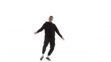 Siyah eşofmanlı genç adam güçlü bir şekilde hip hop, serbest stil, sokak dansı yapıyor. Karmaşık hareketler yapıyor.